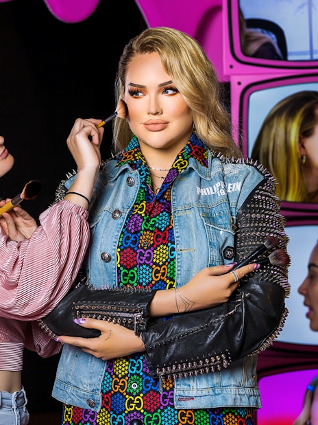 Makeup artist applying blush to wax figure at Madame Tussauds Amsterdam.
