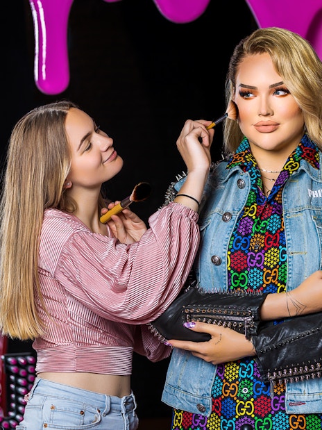 Makeup artist applying blush to wax figure at Madame Tussauds Amsterdam.
