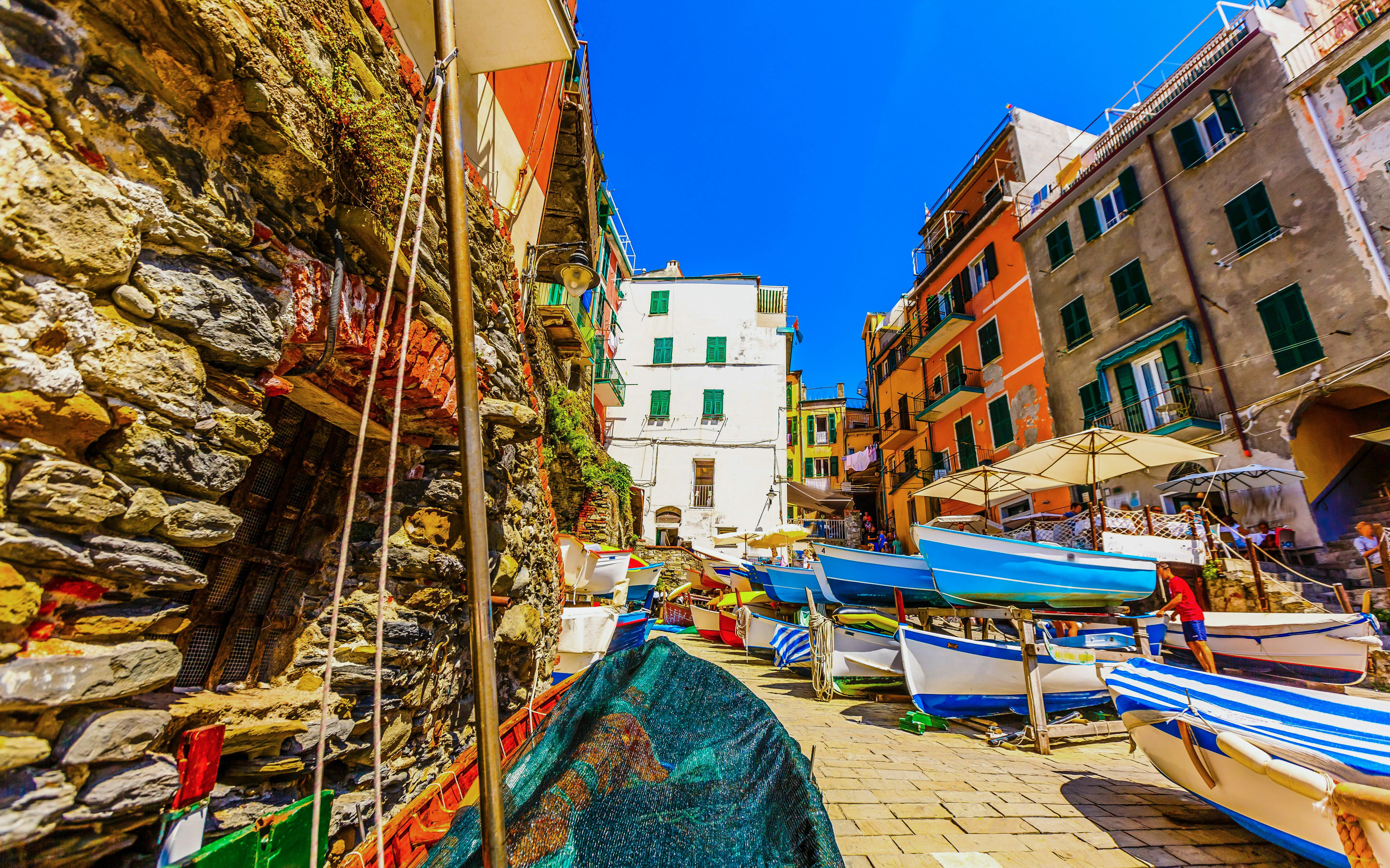 Boats lined up in a colorful street of Riomaggiore, Cinque Terre, Liguria, Italy.