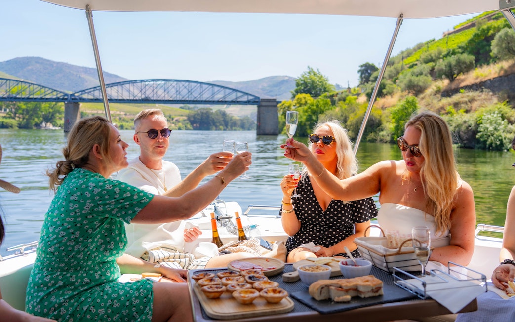 Tourists toasting with wine on a boat in Douro Valley, Portugal.
