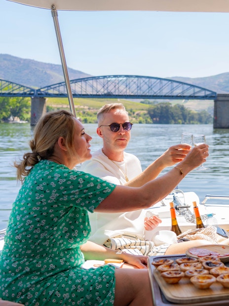Tourists toasting with wine on a boat in Douro Valley, Portugal.