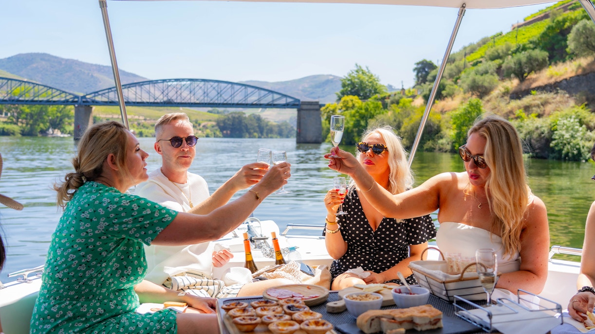 Tourists toasting with wine on a boat in Douro Valley, Portugal.