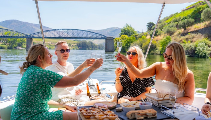Tourists toasting with wine on a boat in Douro Valley, Portugal.