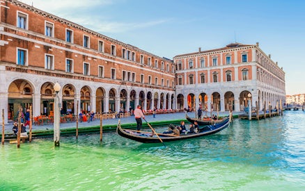 Gondola with passengers on a canal in Venice during evening shared ride.