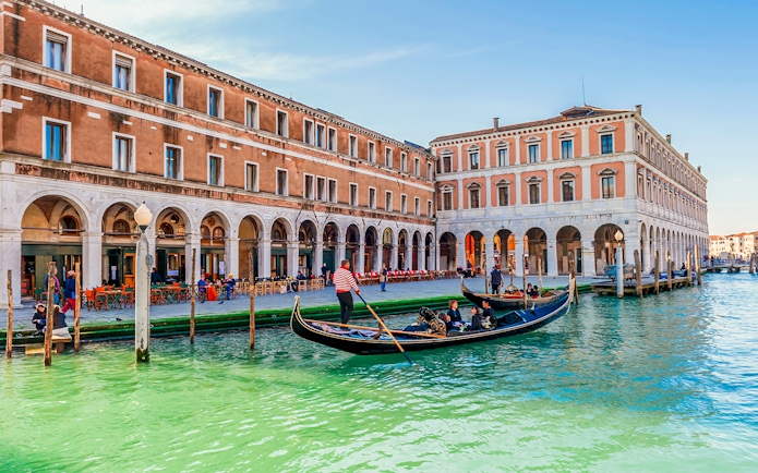Gondola with passengers on a canal in Venice during evening shared ride.