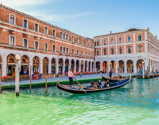Gondola gliding through Venice canal at dawn during winter.