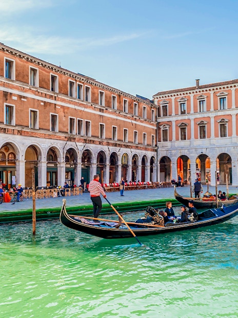 Gondola with passengers on a canal in Venice during evening shared ride.