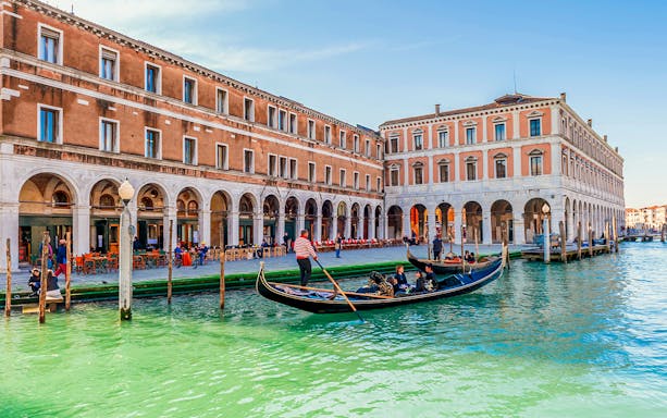 Gondola with passengers on a canal in Venice during evening shared ride.