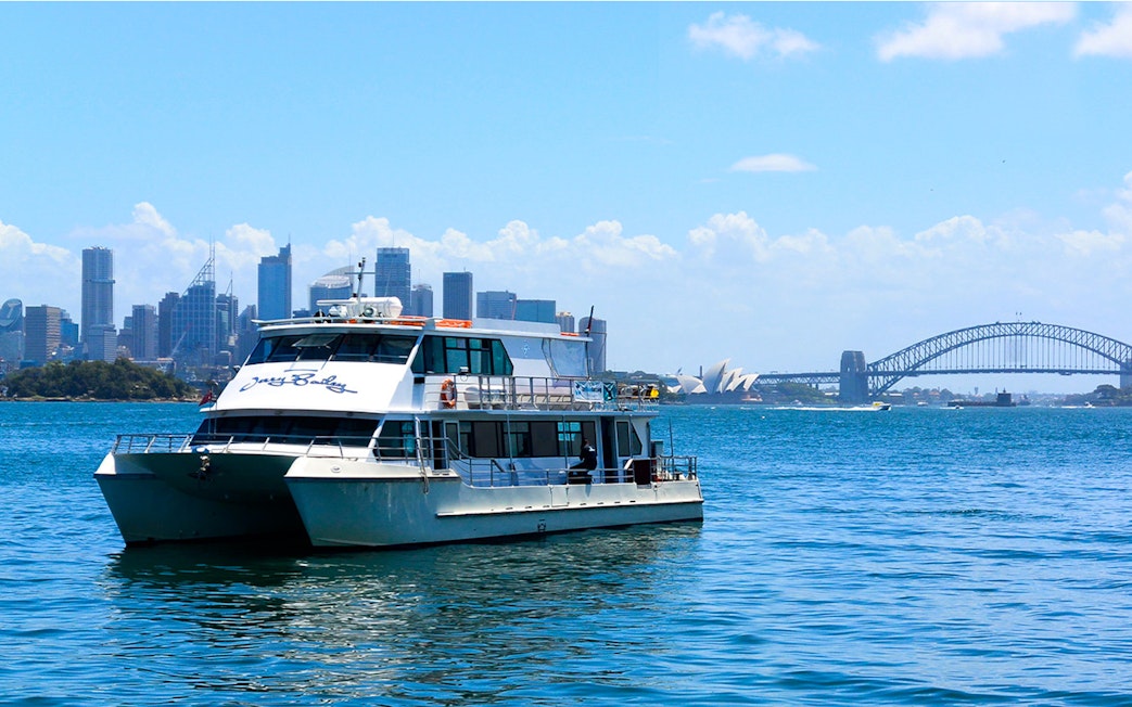 Cruise boat on Sydney Harbour with Opera House and Harbour Bridge in background.