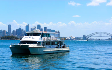 Cruise boat on Sydney Harbour with Opera House and Harbour Bridge in background.