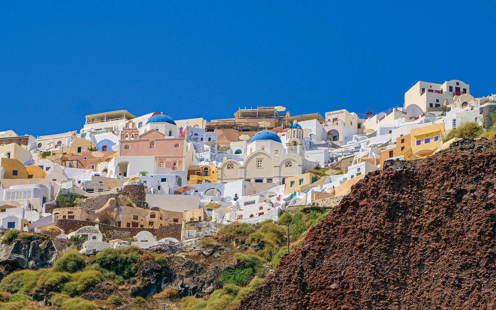 Santorini boat near volcanic islands with tourists hiking volcano and visiting hot springs.