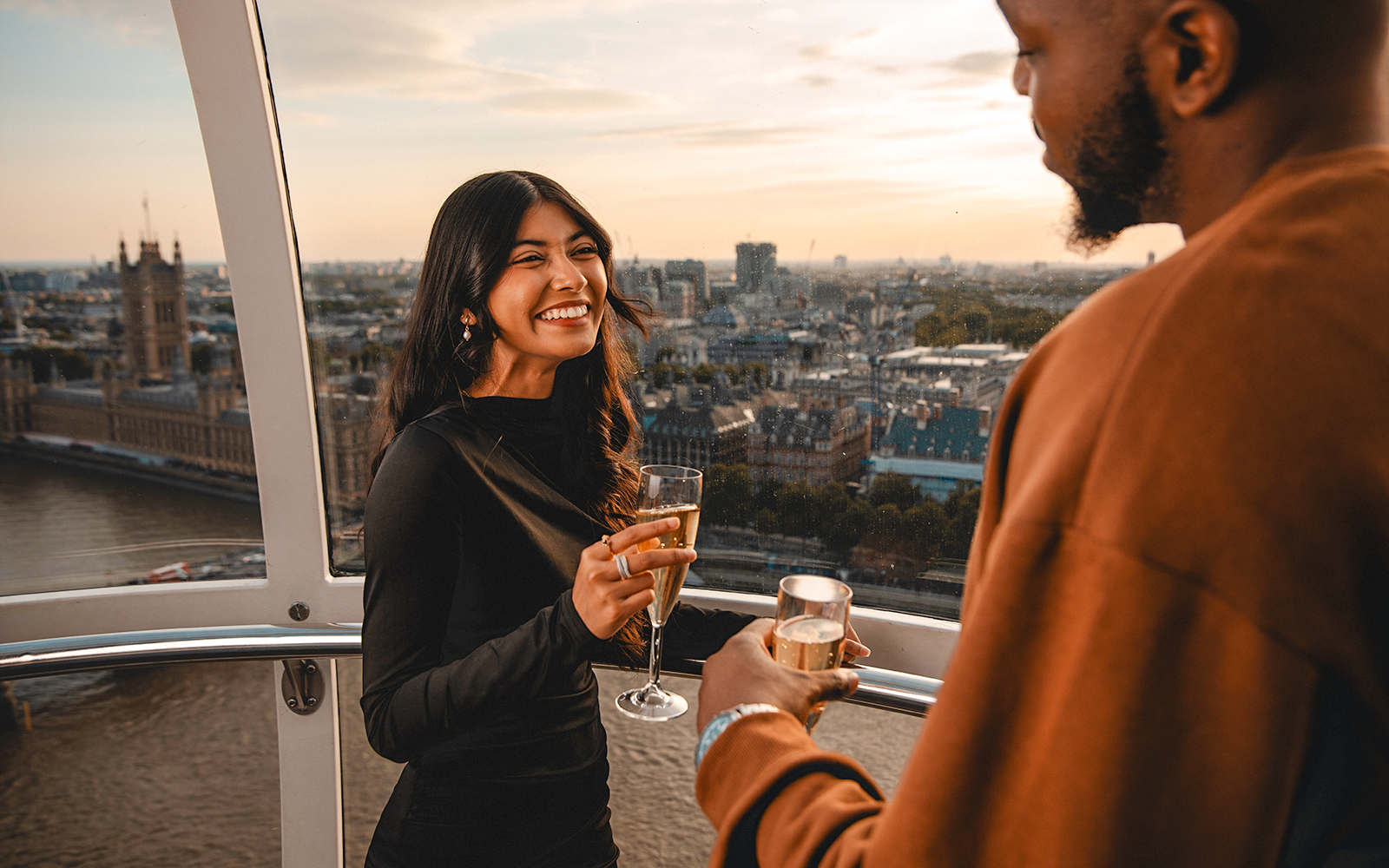 Couple enjoying champagne on the London Eye with cityscape view.