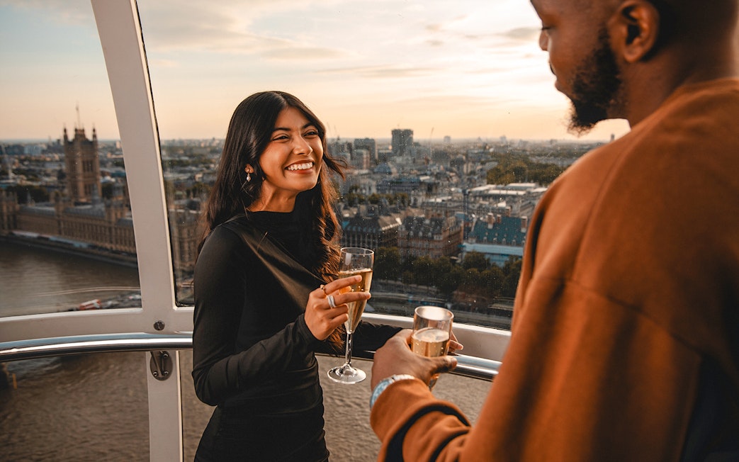 Couple enjoying champagne on the London Eye with cityscape view.