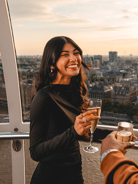 Couple enjoying champagne on the London Eye with cityscape view.