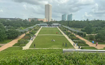 Houston Museum District park with visitors walking along pathways, tall buildings in the background.