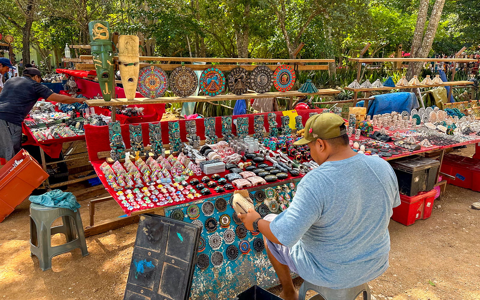 Vendors selling souvenirs outside Chichen Itza temple, including masks and crafts.