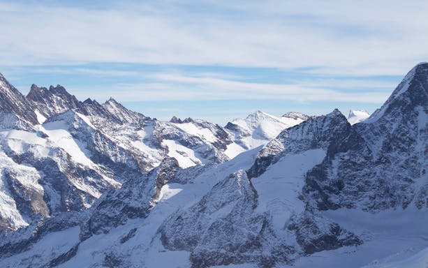 Snow-covered peaks of the Jungfraujoch in the Swiss Alps under a clear sky.