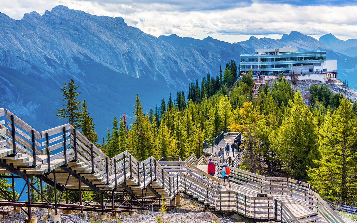 Guests walking on wooden boardwalk to summit station, Sulphur Mountain, Banff.