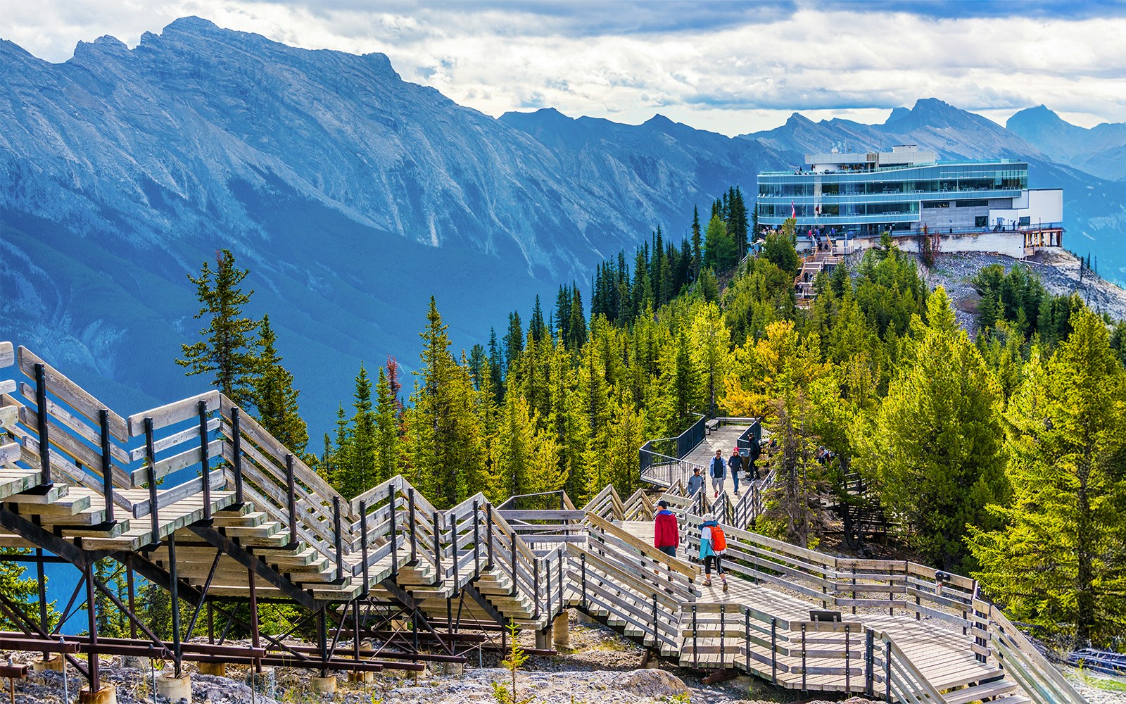 Guests walking on wooden boardwalk to summit station, Sulphur Mountain, Banff.