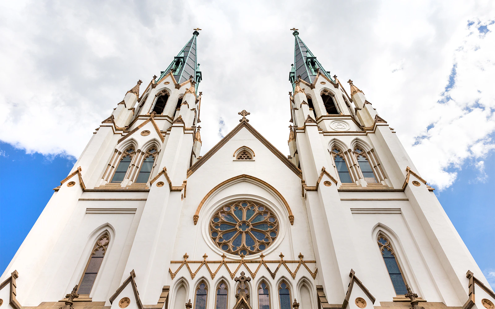 Cathedral of St John the Baptist's twin spires against a cloudy sky in Savannah, GA.