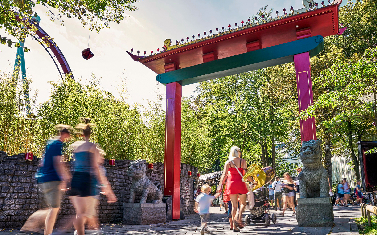Visitors walking under a colorful archway at Tivoli Gardens, Copenhagen.