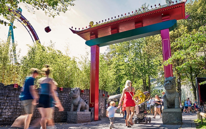 Visitors walking under a colorful archway at Tivoli Gardens, Copenhagen.