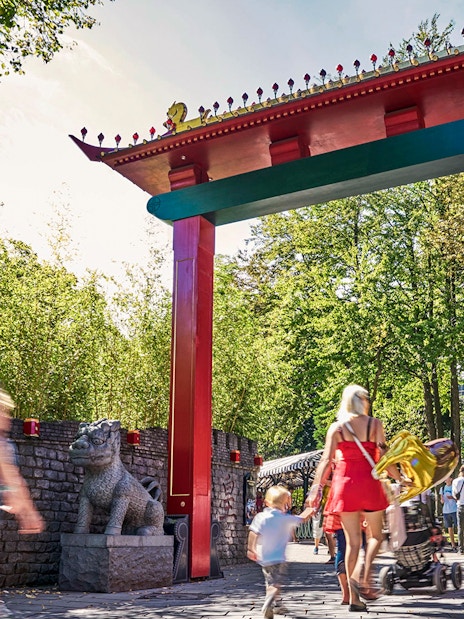 Visitors walking under a colorful archway at Tivoli Gardens, Copenhagen.