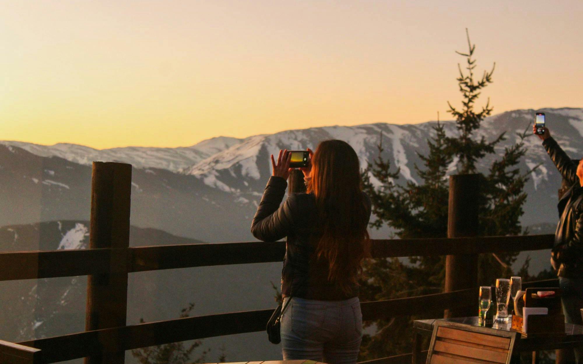 Tourist photographing sunset over Andes Mountains near Valle Nevado, Chile.