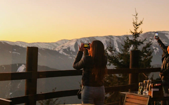 Tourist photographing sunset over Andes Mountains near Valle Nevado, Chile.