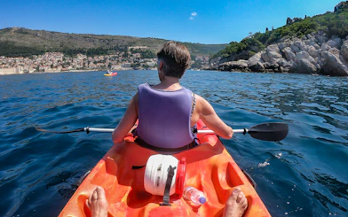Kayaker paddling near Old Town Walls with coastal view.