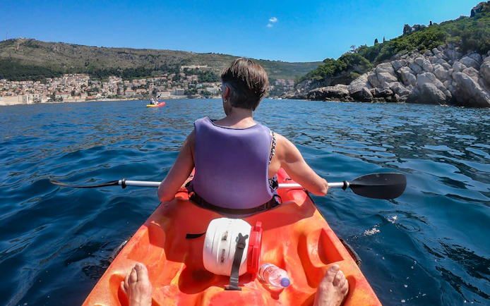 Kayaker paddling near Old Town Walls with coastal view.