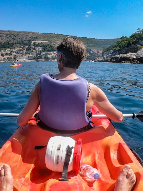 Kayaker paddling near Old Town Walls with coastal view.