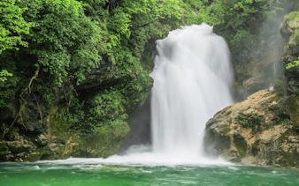 Waterfall at Vintgar Gorge surrounded by lush greenery, Slovenia.