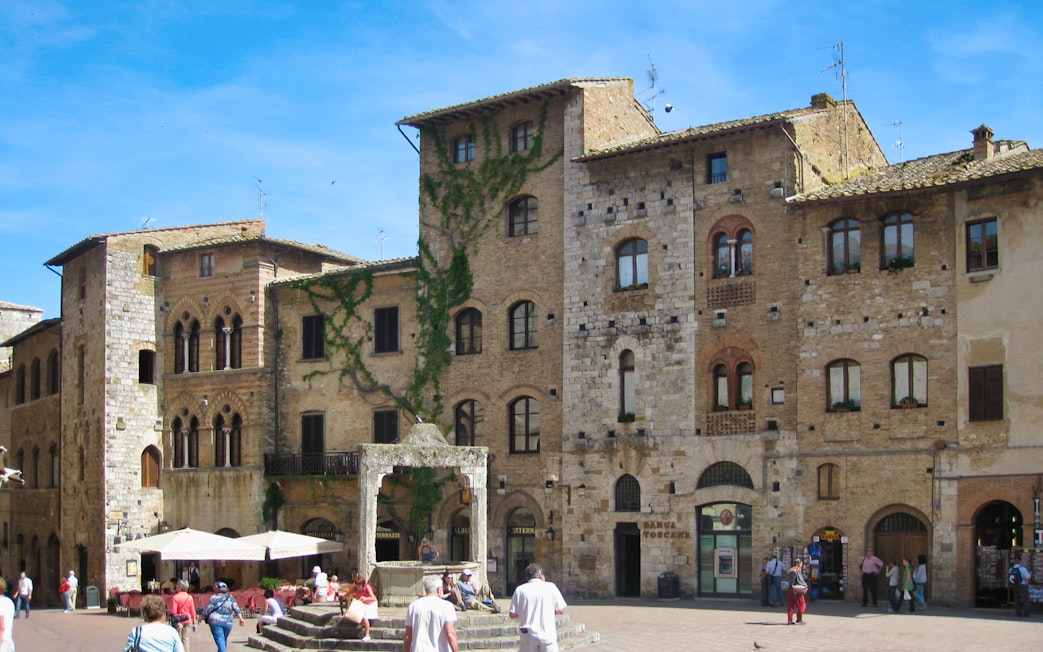 San Gimignano town square with medieval buildings and tourists exploring.