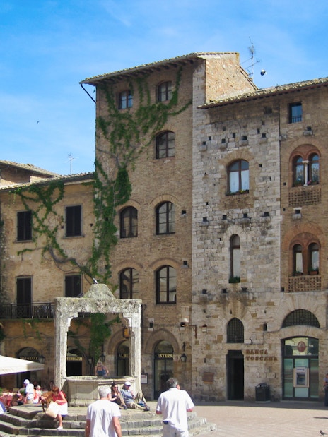 San Gimignano town square with medieval buildings and tourists exploring.
