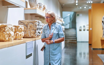 Woman observing ancient artifacts in National Archaeological Museum, Athens.