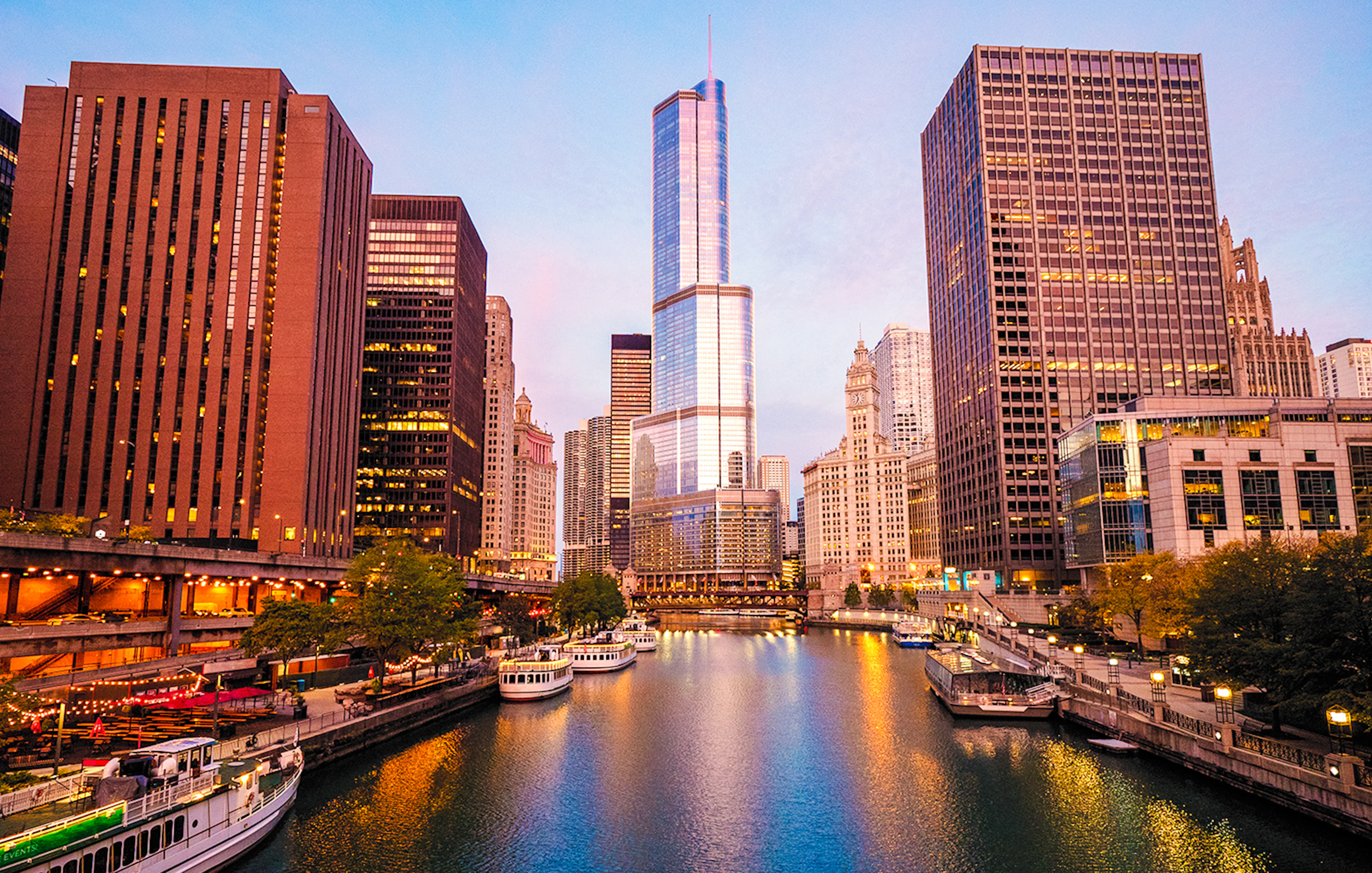 Moored tour boats on the Chicago River at sunrise with city skyline.