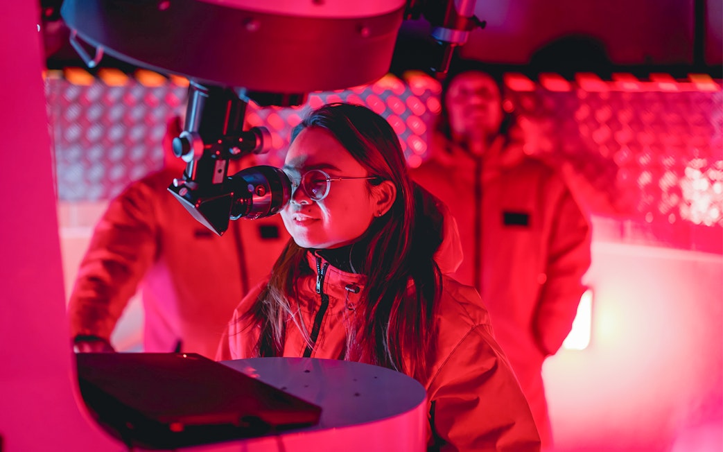 Person observing through telescope at The Crater Stargazing Experience.