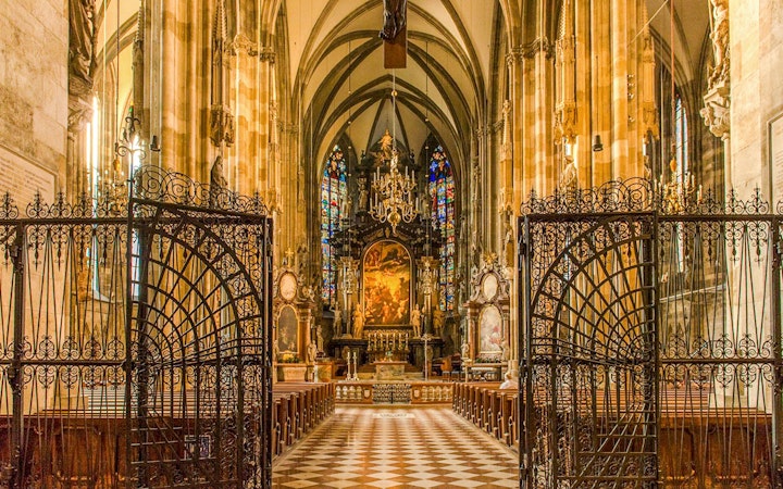 Interior view of St. Stephen's Cathedral in Vienna, featuring ornate gates and stained glass windows.