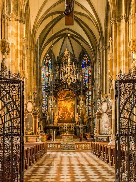 Interior view of St. Stephen's Cathedral in Vienna, featuring ornate gates and stained glass windows.