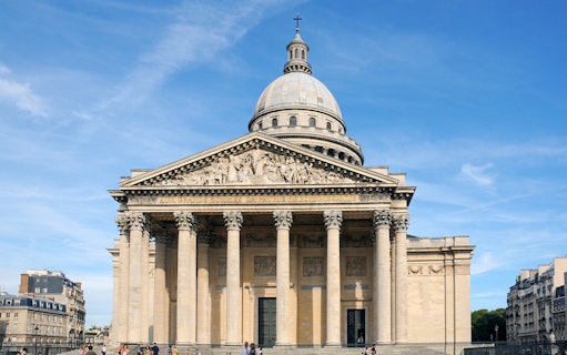 Paris Pantheon exterior with neoclassical columns and dome under a clear sky.