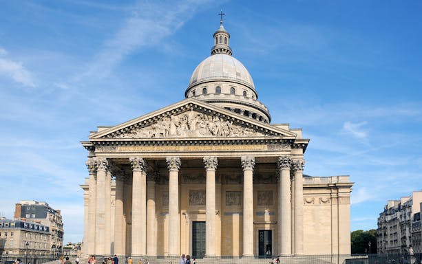 Paris Pantheon exterior with neoclassical columns and dome under a clear sky.