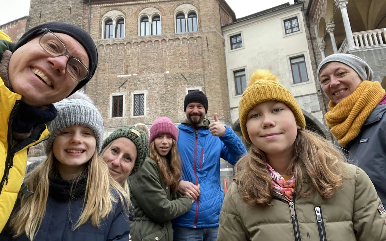 Group enjoying a self-guided city exploration game in front of historic building in Padua.