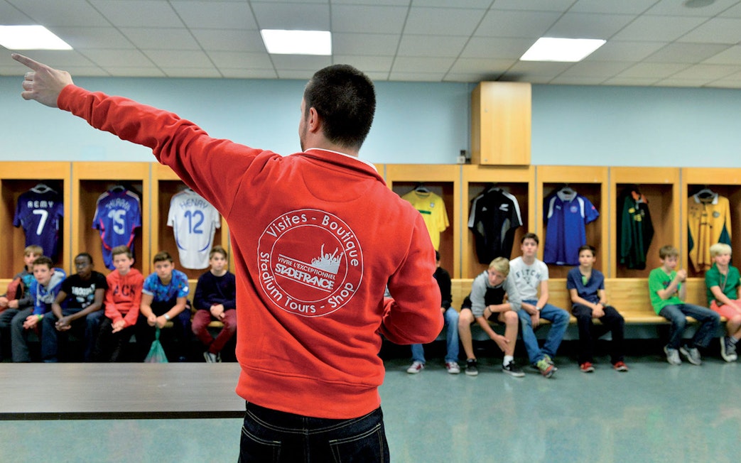 Guide leading a tour group in the Stade de France locker room, Paris.