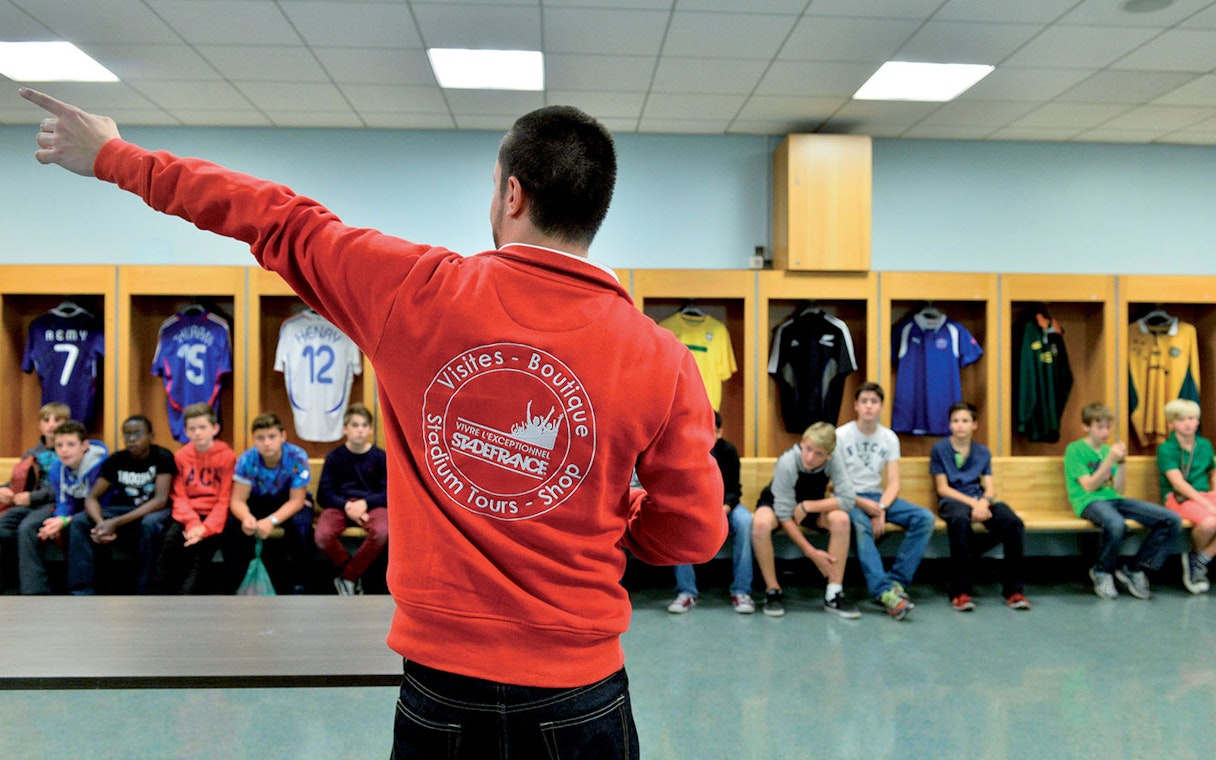 Guide leading a tour group in the Stade de France locker room, Paris.