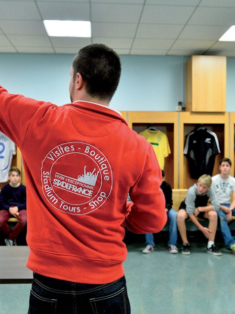 Guide leading a tour group in the Stade de France locker room, Paris.