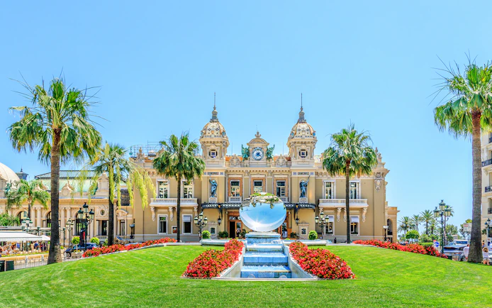 Monte Carlo Casino facade with fountain and palm trees in the square.