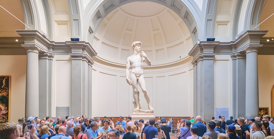 Visitors at Accademia Gallery in Florence viewing Michelangelo's David statue.