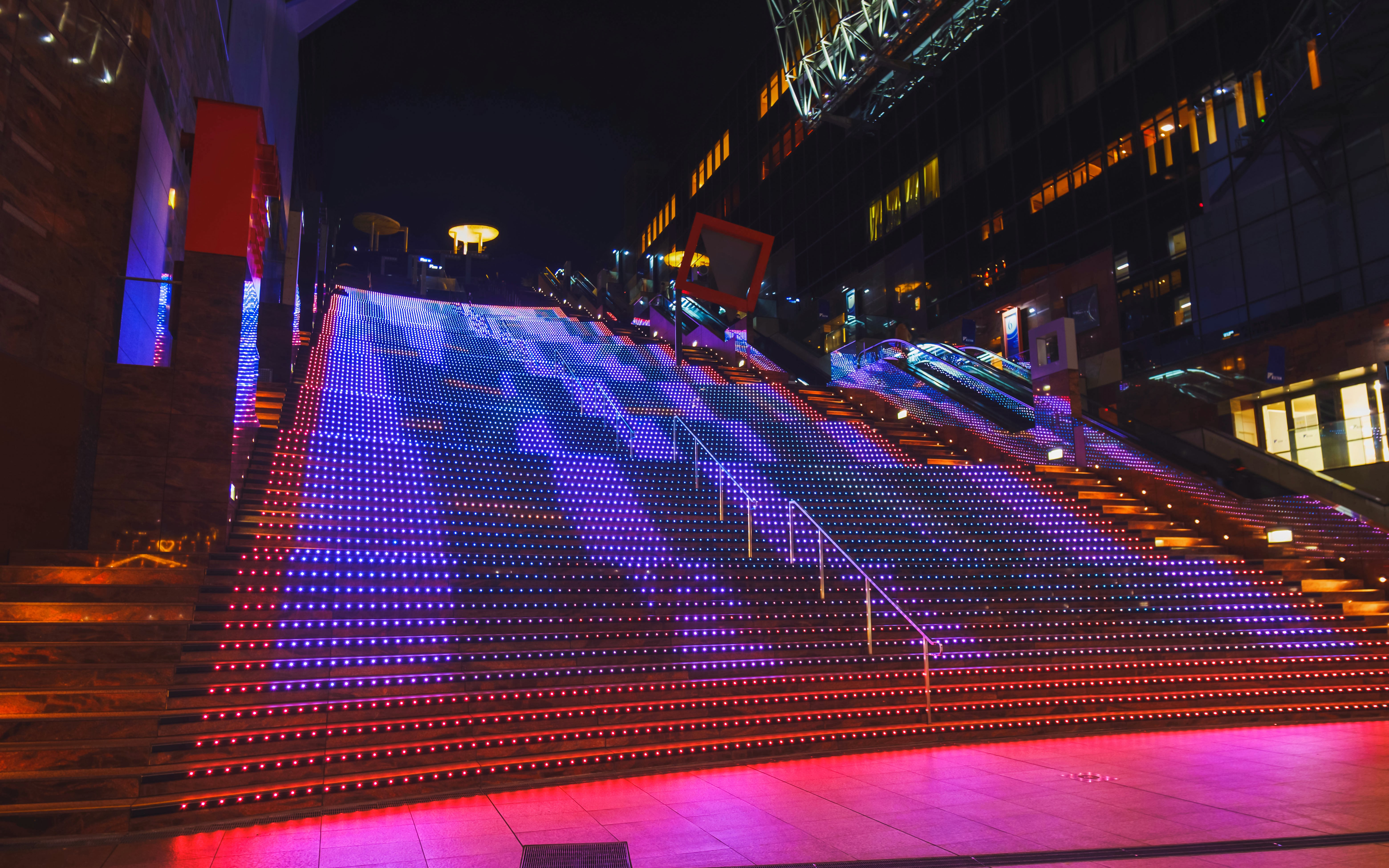 Kyoto Station's Daikandan light show illuminating colorful LED stairs at night.