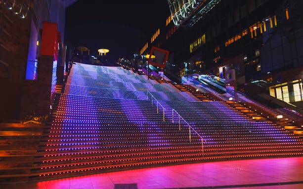 Kyoto Station's Daikandan light show illuminating colorful LED stairs at night.